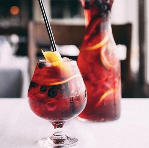 Glass and jug of a festive blueberry sangria